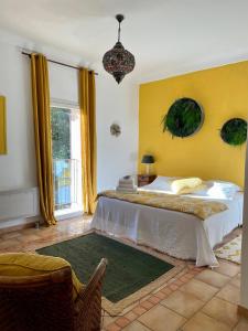 - une chambre avec un grand lit et un mur jaune dans l'établissement Mas de la Sacristière, à Jonquerettes