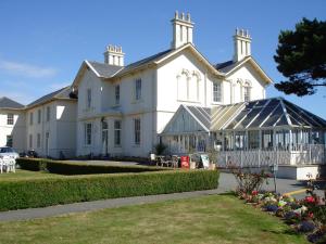 a large white house with a conservatory in front of it at Les Cotils in Saint Peter Port