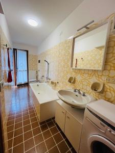 a bathroom with a sink and a washing machine at San Luigi - Rooms & Apartments in Campodolcino