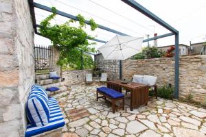 a patio with a table and chairs and an umbrella at Mala House - Šolta Island in Grohote