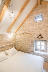 a bedroom with a white bed and a brick wall at Mala House - Šolta Island in Grohote