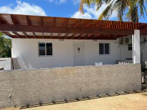 ein Haus mit einer Ziegelwand und einer hölzernen Pergola in der Unterkunft Romantic place savaneta near several beaches in Savaneta