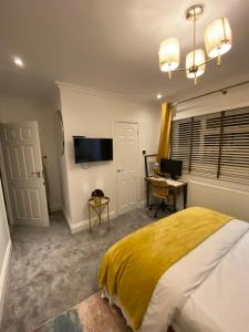 a bedroom with a bed and a desk and a television at En-suite cheerful room. in Hanworth