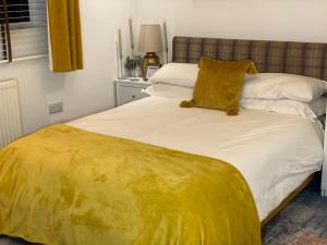 Una cama con una manta amarilla encima. en En-suite cheerful room. en Hanworth