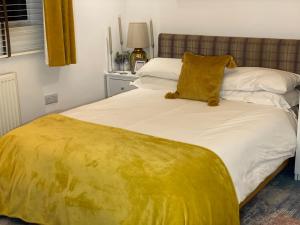 a bed with a yellow blanket on top of it at En-suite cheerful room. in Hanworth
