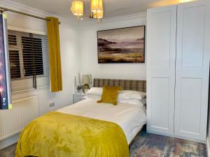 a bedroom with a bed with a yellow blanket on it at En-suite cheerful room. in Hanworth