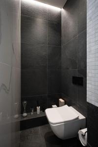 baño con aseo y pared de azulejos negros en HOUSE38 Panoramic View Apartments SELF CHECK-IN, en Kaunas