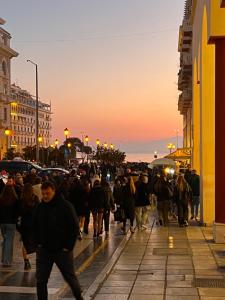 uma multidão de pessoas andando por uma rua ao pôr do sol em Small budget diamond apartment in Agias Sofias. em Tessalônica