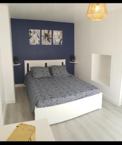 Ile de Saint-Nicolas T2 et/ou Ile de Penfret Studio في فوسنان: غرفة نوم بها سرير وجدار أزرق