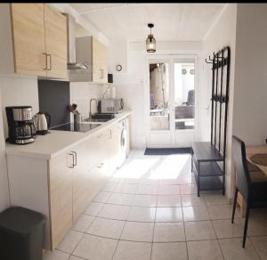 Ile de Saint-Nicolas T2 et/ou Ile de Penfret Studio في فوسنان: مطبخ بدولاب بيضاء وأرضية بلاط +7 صور