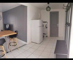 cocina con nevera, mesa y sillas en Ile de Saint-Nicolas T2 et/ou Ile de Penfret Studio, en Fouesnant