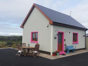 uma pequena casa branca com uma mesa e cadeiras em Peaceful Haven on the Wild Atlantic Way em Miltown Malbay