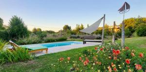 una piscina en un jardín con un banco y flores en Las Rosas en Balneario Mar Azul