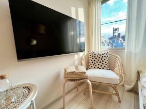 uma sala de estar com uma cadeira e uma televisão na parede em TYO Ikebukuro Designer’s Apt 303 em Tóquio