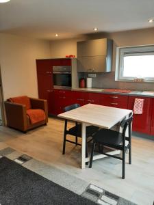 een keuken met rode kasten en een tafel en stoelen bij Appartement Oase in Klimmen