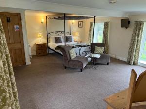 a bedroom with a bed and two chairs and a table at The Coppleridge Inn in Motcombe