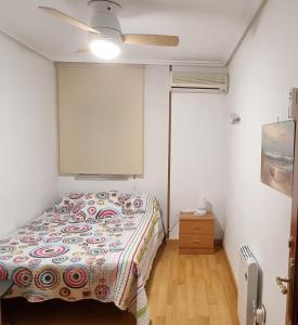 Apartamento Plasencia Illuminati في بلاسينثيا: غرفة نوم بسرير ومروحة سقف