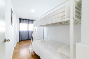 a white bedroom with a bunk bed and a door at Piso en Palacio Quinta Alegre in Granada