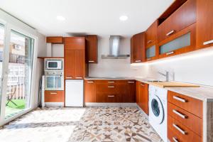 a kitchen with wooden cabinets and a washer and dryer at Piso en Palacio Quinta Alegre in Granada