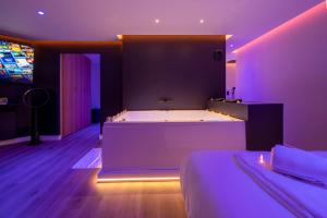 Dormitorio con bañera grande en habitación púrpura en LA BULLE DÉTENTE / BALNÉO - SAUNA en La Riche