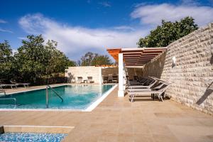 una piscina con sedie a sdraio accanto a un muro di mattoni di Pansion Lavanda Lopar a Lopar