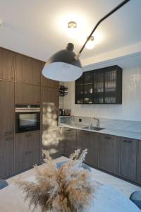 una cocina con armarios de madera y una gran lámpara. en A T Ò K V Ė P I S en Nida