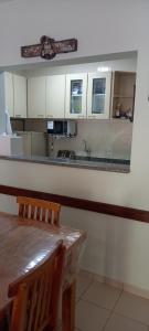 uma cozinha com armários brancos, uma mesa e um espelho em Apartamento Climatizado a 150 Metros da Praia em Ubatuba
