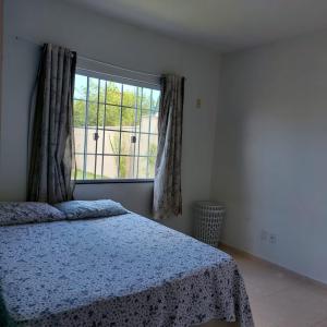 a bedroom with a bed and a large window at Casa 4/4 com piscina. in Maricá