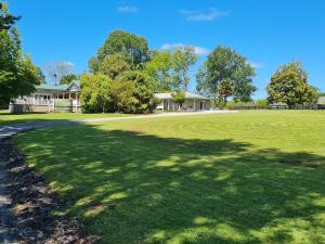 un gran campo de hierba con una casa en el fondo en The Olde Store - Hunua Holiday Home en Hunua