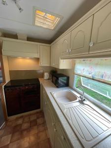 eine Küche mit weißen Schränken, einem Waschbecken und einem Fenster in der Unterkunft Le Murmont in Thonnance-lès-Joinville