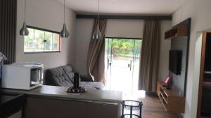 a kitchen and living room with a couch and a microwave at Casa de Praia, pé na areia Guaratiba Prado - Bahia in Prado