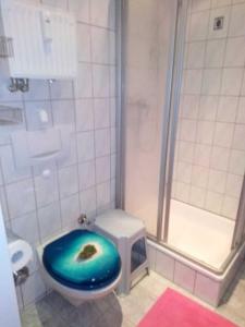 ein Badezimmer mit einem blauen WC und einer Dusche in der Unterkunft SPO - gemütliches Apartment - TOP LAGE in Sankt Peter-Ording