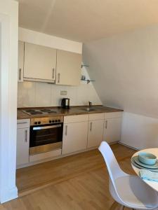 a kitchen with white cabinets and a table and a chair at Modernes, familienfreundliches Apartment in Lübeck in Lübeck