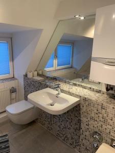a bathroom with a sink and a toilet and a mirror at Modernes, familienfreundliches Apartment in Lübeck in Lübeck