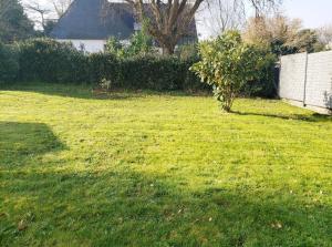 a yard with green grass and a white fence at Ile Cigogne in Fouesnant