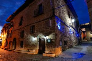 un antiguo edificio de piedra con luces azules en una calle en Hospederia Jaramillo, en Peñaranda de Duero