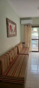 uma sala de estar com um sofá e uma janela em Apartamento Climatizado a 150 Metros da Praia em Ubatuba