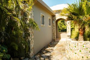 a house with a palm tree and a stone wall at Aleli Cottages in Culebra