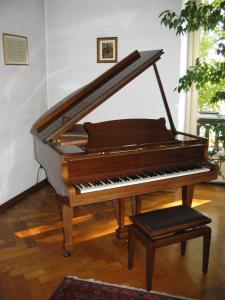un piano sentado en una sala de estar con un taburete en Al Porta Susa B&B, en Turín