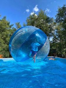 a boy in a large blue ball in the water at Domki Fala in Dąbki