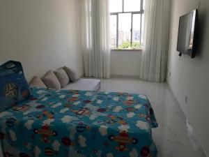 um quarto com uma cama com um edredão azul em Quartos em APART FAMILIAR no circuito do carnaval de Salvador em Salvador