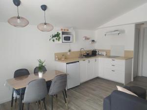 kuchnia ze stołem i krzesłami oraz kuchnia z białymi szafkami w obiekcie Le Petit Pied à Terre du Luberon w mieście Mérindol