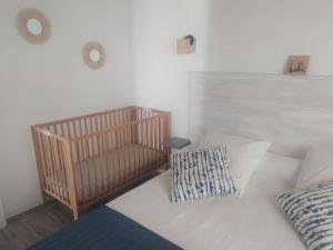 uma cama branca com um berço num quarto em Pied à terre familial au pied du Luberon em Mérindol