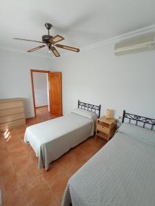 - une chambre avec 2 lits et un ventilateur de plafond dans l'établissement Casa Rural El Algarrobo, à Utrera