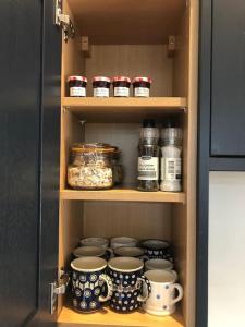 a cupboard with jars and mugs and cups and jarsearcher at The Stables in Colchester