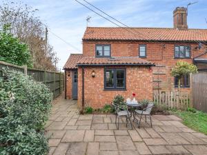 a brick house with a table and chairs in a yard at Hare Cottage in North Tuddenham