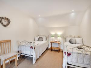 a bedroom with two beds and a table and a chair at Hare Cottage in North Tuddenham