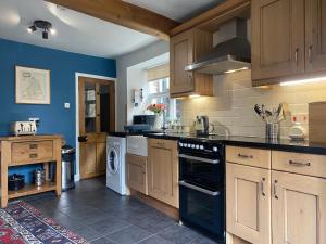 a kitchen with wooden cabinets and black appliances at Alnwick Holiday House - Charming, Historic, Central Alnwick with Courtyard in Alnwick
