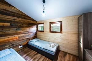 um quarto com uma cama numa parede de madeira em Domek Trolla em Sieraków
