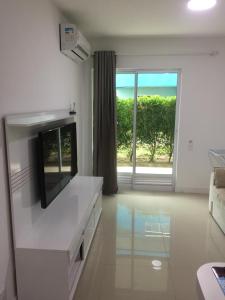 a white living room with a tv and a window at Golden Lake - Vista Lagoa in Arraial do Cabo